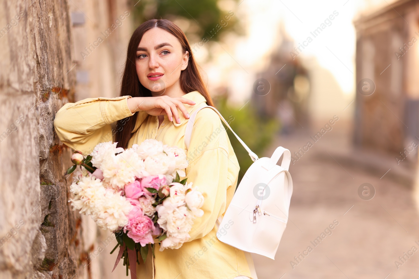 Woman with bouquet of beautiful peonies on city street. Space for text Photo of Woman with bouquet of beautiful peonies on city street. Space for text