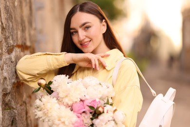 Photo of Woman with bouquet of beautiful peonies on city street