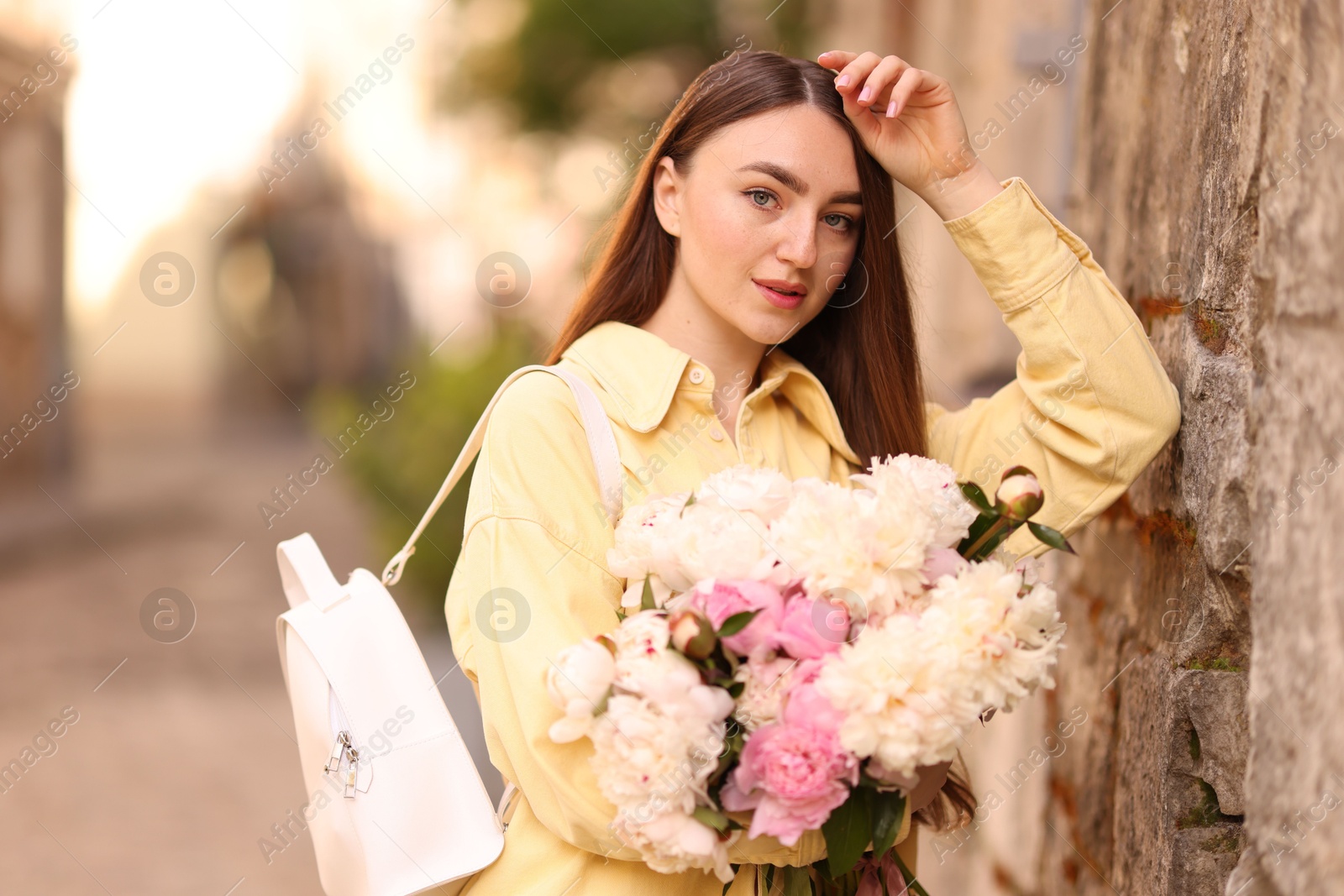 Woman with bouquet of beautiful peonies on city street Photo of Woman with bouquet of beautiful peonies on city street