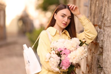 Photo of Woman with bouquet of beautiful peonies on city street