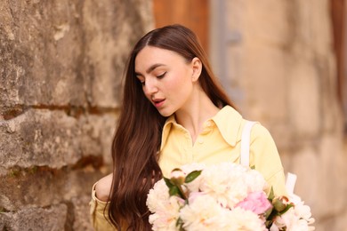 Photo of Woman with bouquet of beautiful peonies on city street