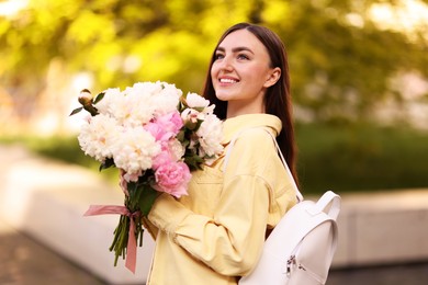 Photo of Woman with bouquet of beautiful peonies on city street