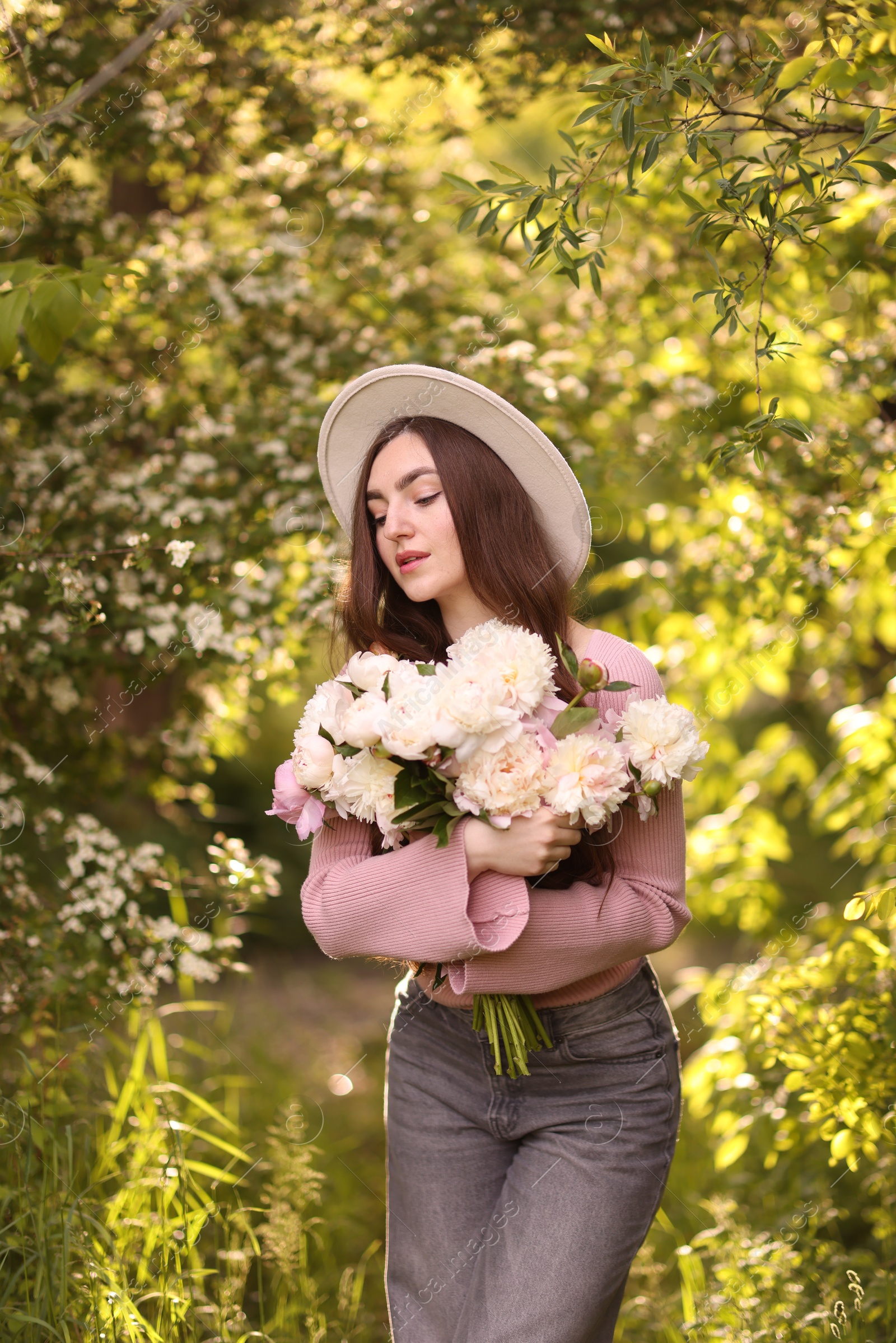 Beautiful woman with bouquet of peonies in park Photo of Beautiful woman with bouquet of peonies in park
