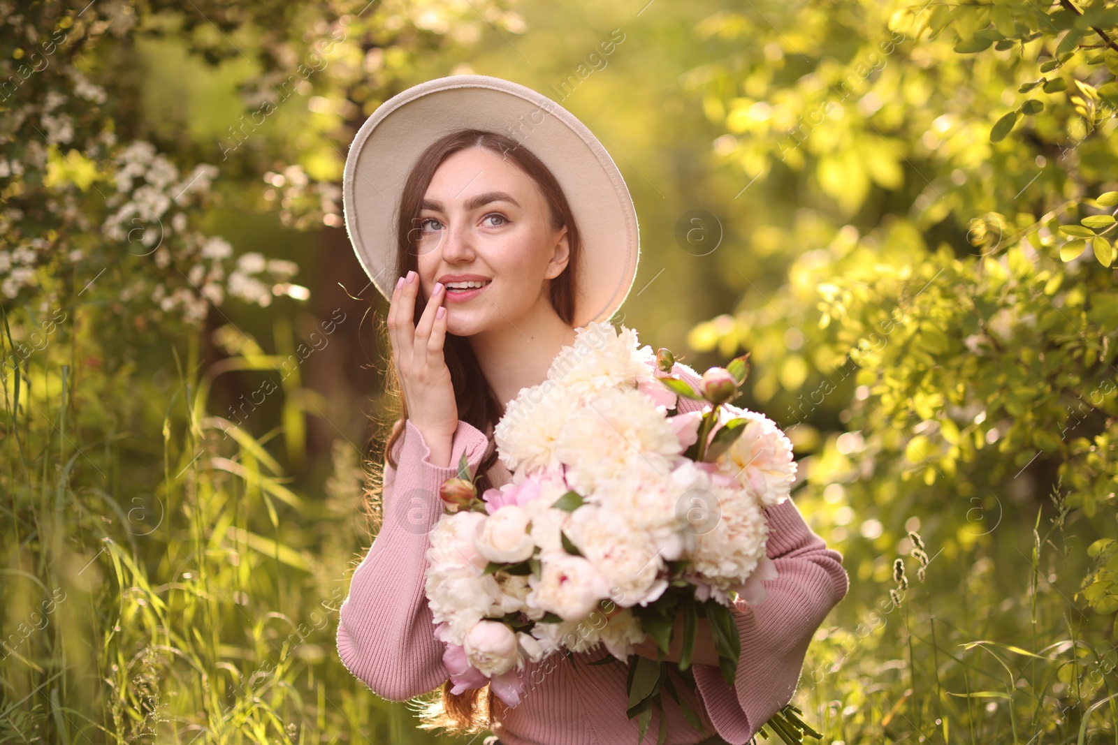 Beautiful woman with bouquet of peonies in park Photo of Beautiful woman with bouquet of peonies in park