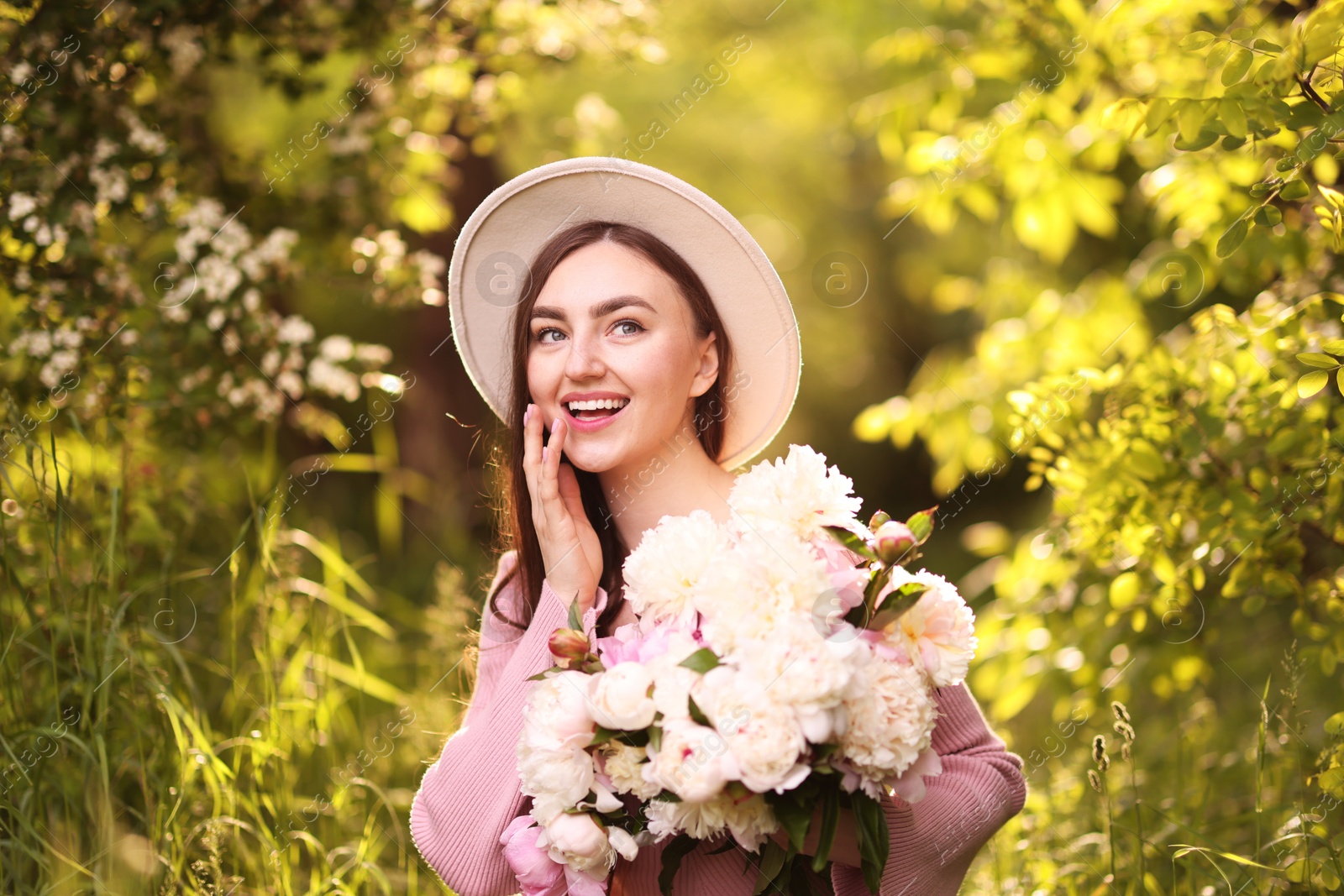 Beautiful woman with bouquet of peonies in park Photo of Beautiful woman with bouquet of peonies in park