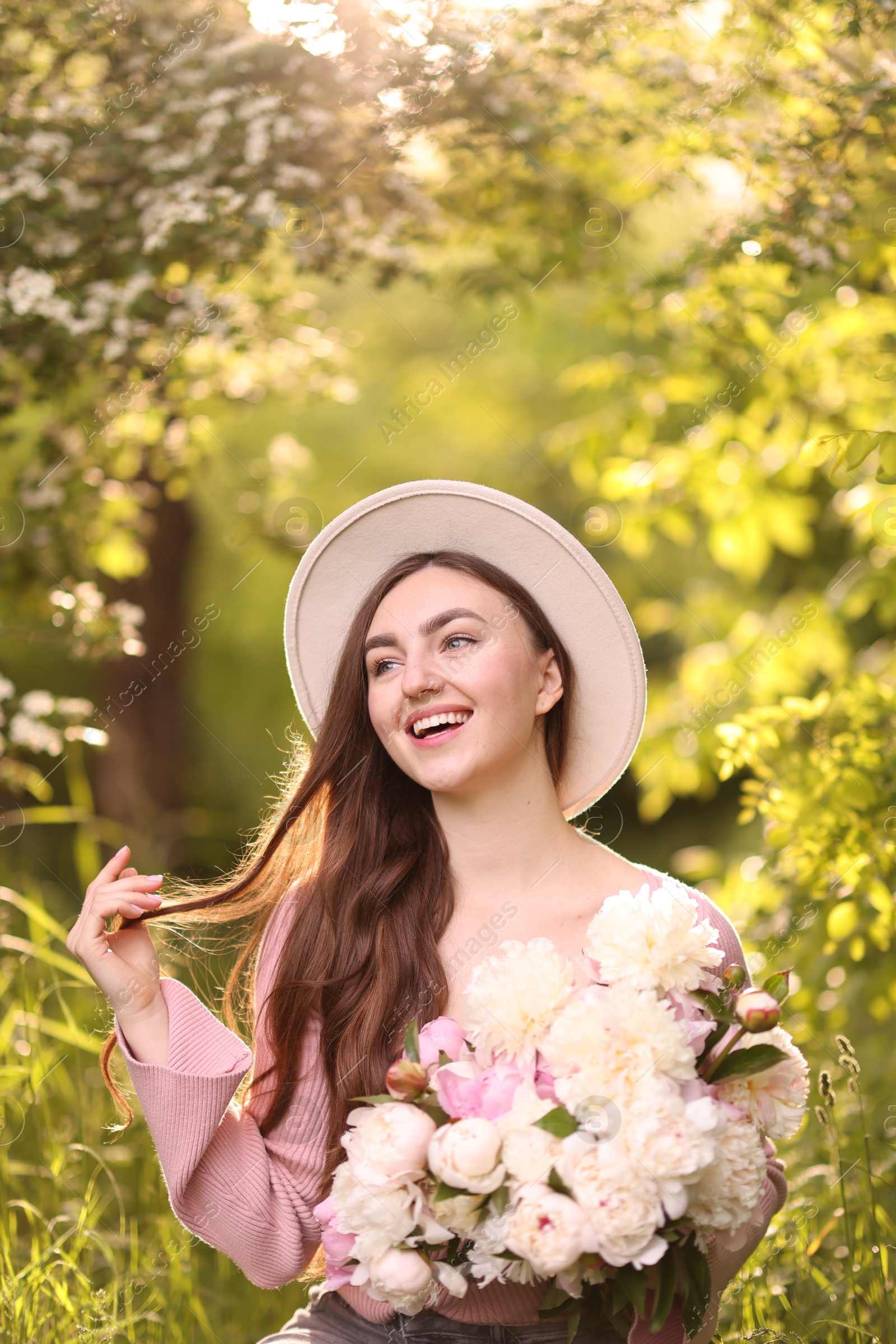 Beautiful woman with bouquet of peonies in park Photo of Beautiful woman with bouquet of peonies in park
