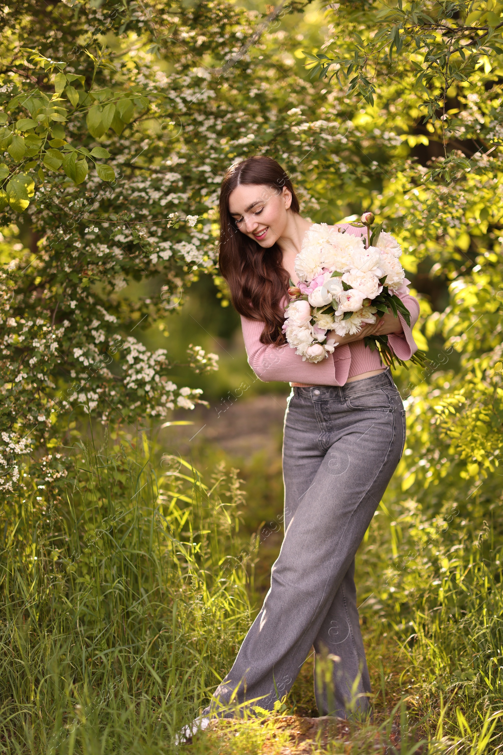 Beautiful woman with bouquet of peonies in park Photo of Beautiful woman with bouquet of peonies in park