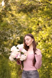 Photo of Beautiful woman with bouquet of peonies in park. Space for text