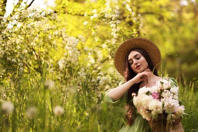 Photo of Beautiful woman with bouquet of peonies in park. Space for text