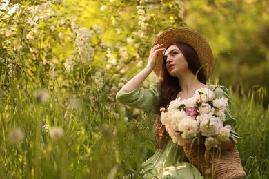 Photo of Beautiful woman with bouquet of peonies in park. Space for text
