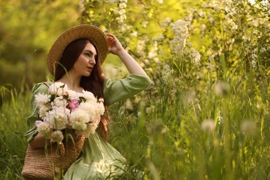 Photo of Beautiful woman with bouquet of peonies in park. Space for text