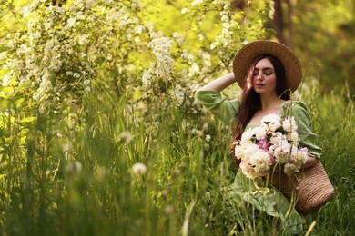 Photo of Beautiful woman with bouquet of peonies in park. Space for text
