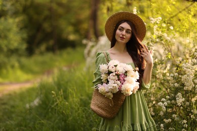 Photo of Beautiful woman with bouquet of peonies in park. Space for text