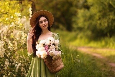 Photo of Beautiful woman with bouquet of peonies in park. Space for text