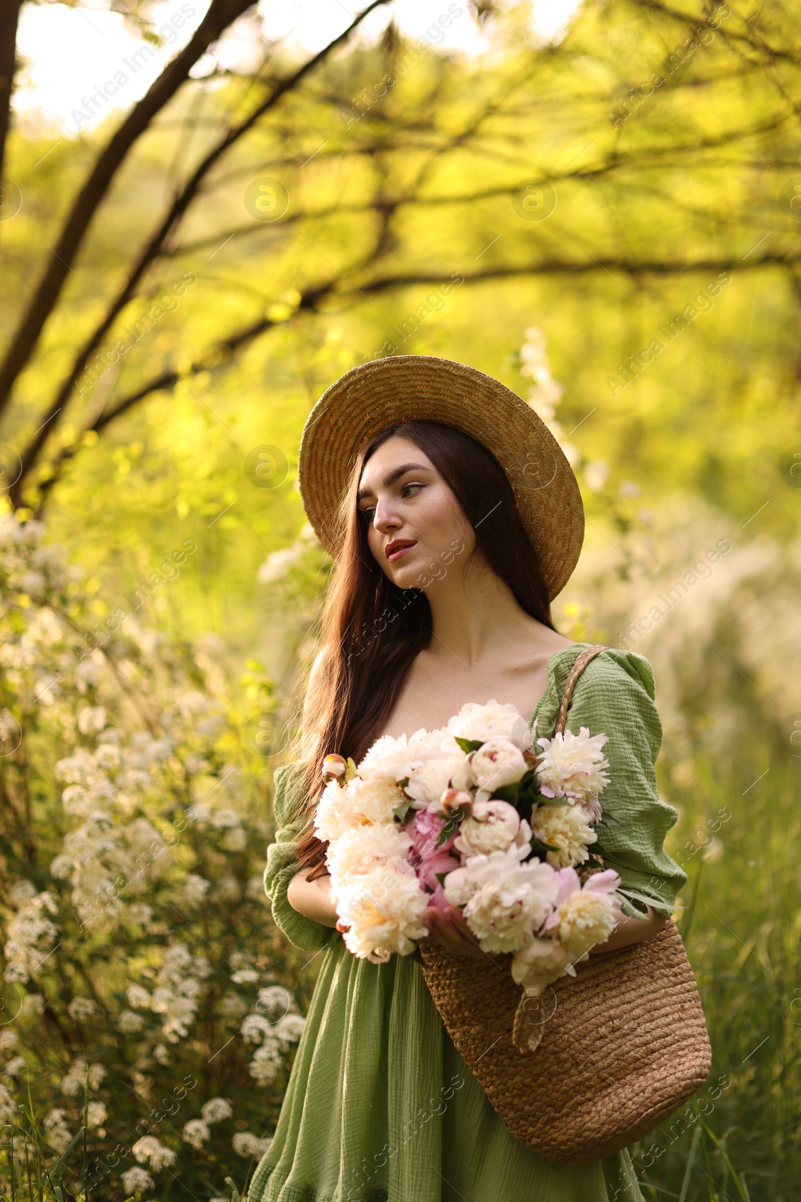 Beautiful woman with bouquet of peonies in park Photo of Beautiful woman with bouquet of peonies in park
