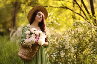 Photo of Beautiful woman with bouquet of peonies in park. Space for text