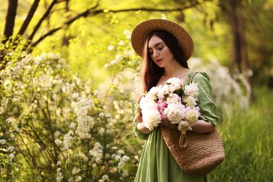 Photo of Beautiful woman with bouquet of peonies in park. Space for text