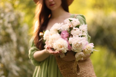 Photo of Beautiful woman with bouquet of peonies in park, closeup