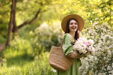 Photo of Beautiful woman with bouquet of peonies in park. Space for text