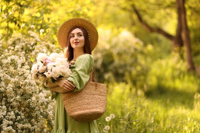 Photo of Beautiful woman with bouquet of peonies in park. Space for text