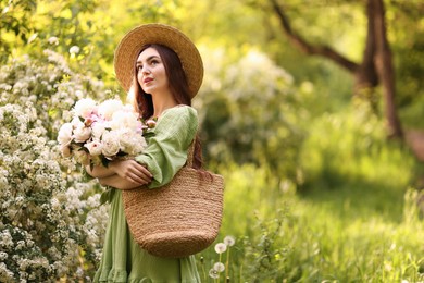 Photo of Beautiful woman with bouquet of peonies in park. Space for text