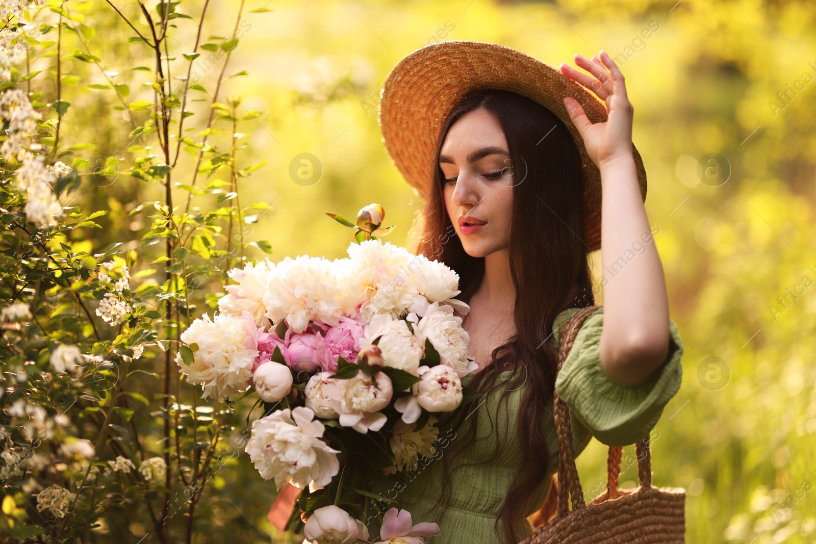Beautiful woman with bouquet of peonies in park Photo of Beautiful woman with bouquet of peonies in park