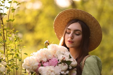 Photo of Beautiful woman with bouquet of peonies in park. Space for text