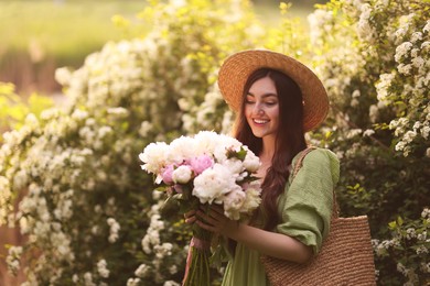 Photo of Beautiful woman with bouquet of peonies in park on sunny day. Space for text