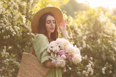 Photo of Beautiful woman with bouquet of peonies in park on sunny day
