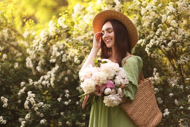 Photo of Beautiful woman with bouquet of peonies in park on sunny day. Space for text