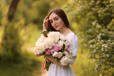 Photo of Beautiful woman with bouquet of peonies in park