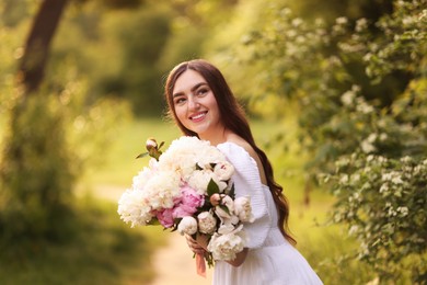 Photo of Beautiful woman with bouquet of peonies in park
