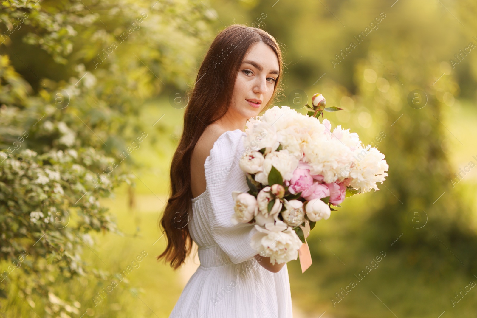 Beautiful woman with bouquet of peonies in park Photo of Beautiful woman with bouquet of peonies in park
