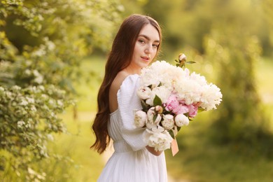 Photo of Beautiful woman with bouquet of peonies in park