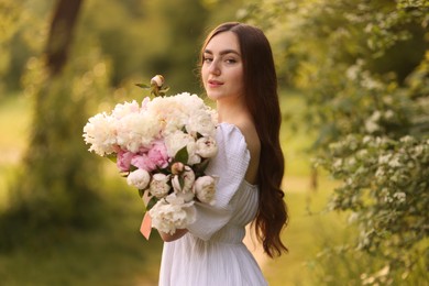 Photo of Beautiful woman with bouquet of peonies in park