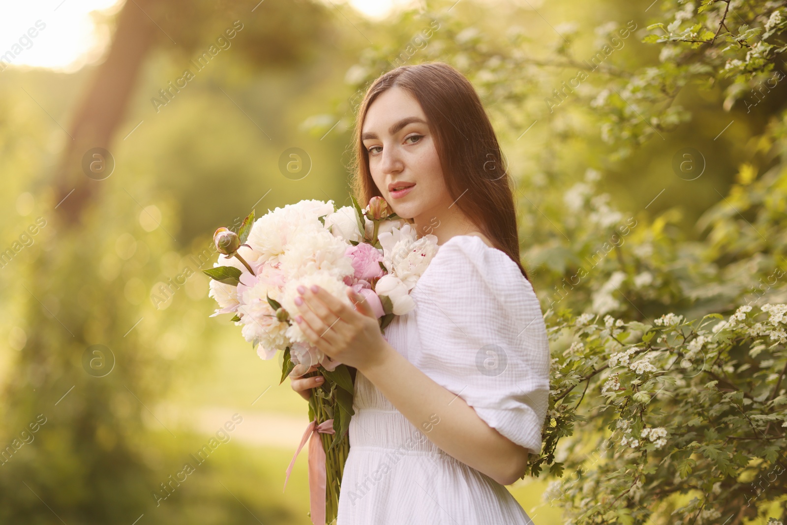 Beautiful woman with bouquet of peonies in park Photo of Beautiful woman with bouquet of peonies in park