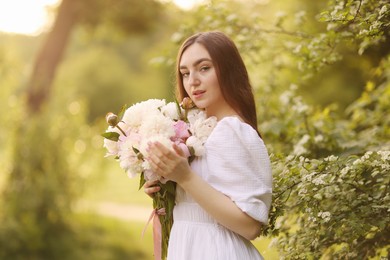 Photo of Beautiful woman with bouquet of peonies in park