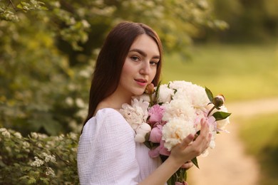 Photo of Beautiful woman with bouquet of peonies in park