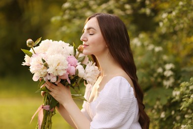Photo of Beautiful woman with bouquet of peonies in park