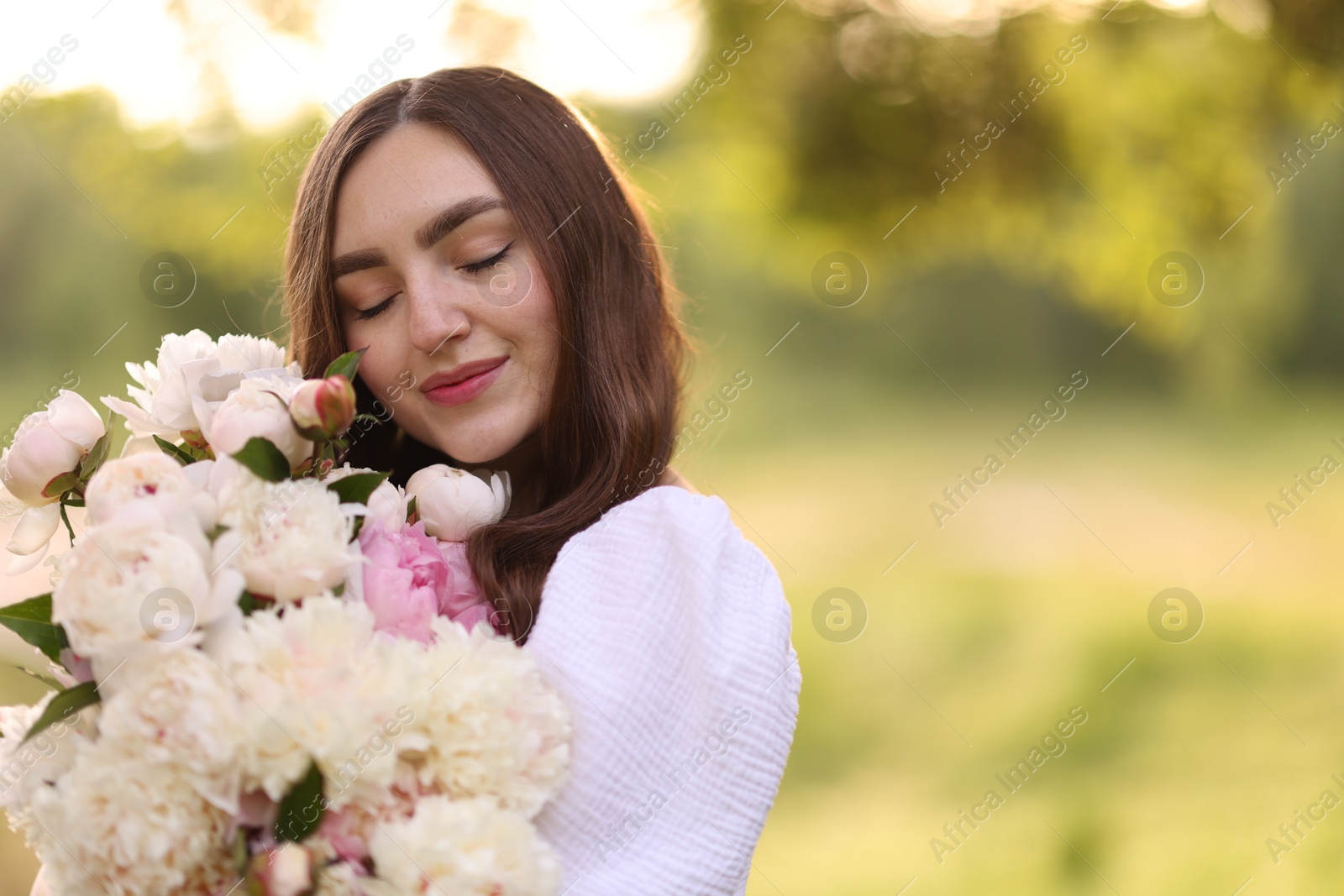 Beautiful woman with bouquet of peonies in park. Space for text Photo of Beautiful woman with bouquet of peonies in park. Space for text