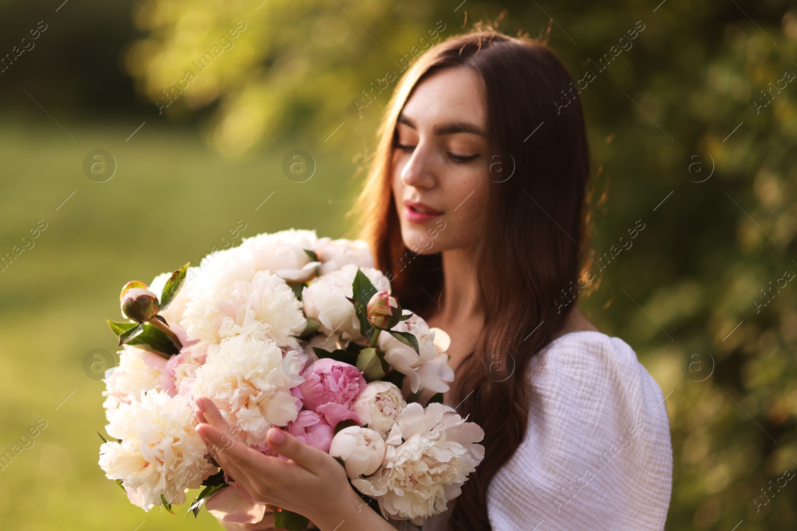 Beautiful woman with bouquet of peonies in park Photo of Beautiful woman with bouquet of peonies in park
