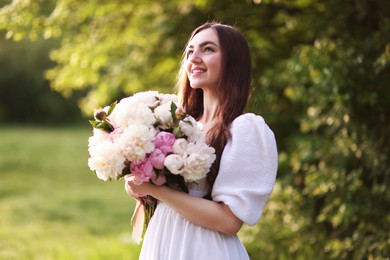 Photo of Beautiful woman with bouquet of peonies in park