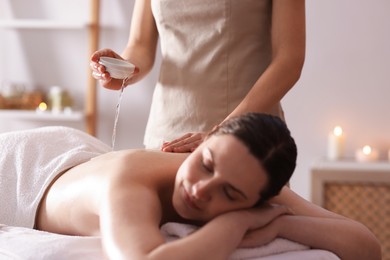 Photo of Woman receiving back massage with oil in spa salon