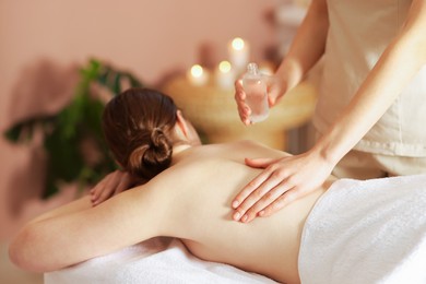 Photo of Woman receiving back massage with oil in spa salon