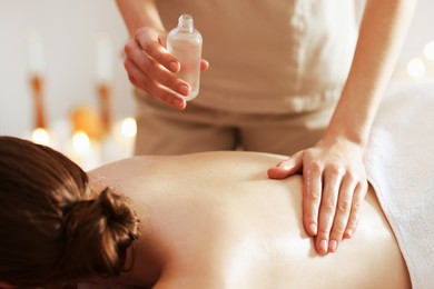 Photo of Woman receiving back massage with oil in spa salon, closeup