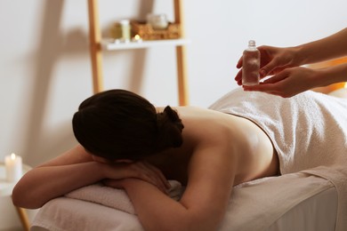 Photo of Woman receiving back massage with oil in spa salon