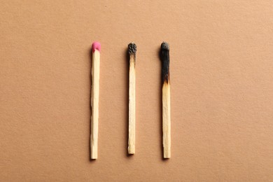 Photo of Burnt and whole matches on beige background, flat lay