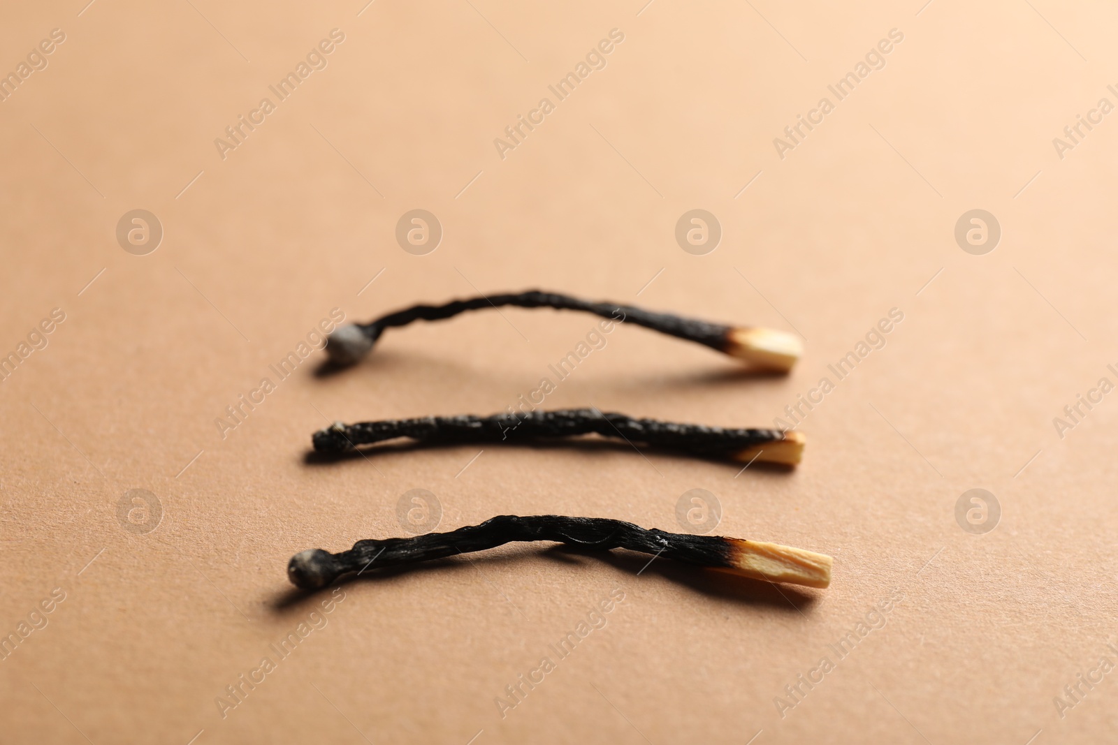 Burnt matches on beige background, closeup view Photo of Burnt matches on beige background, closeup view