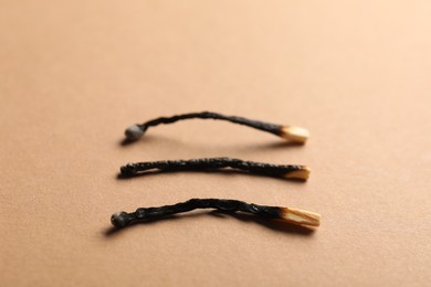 Photo of Burnt matches on beige background, closeup view