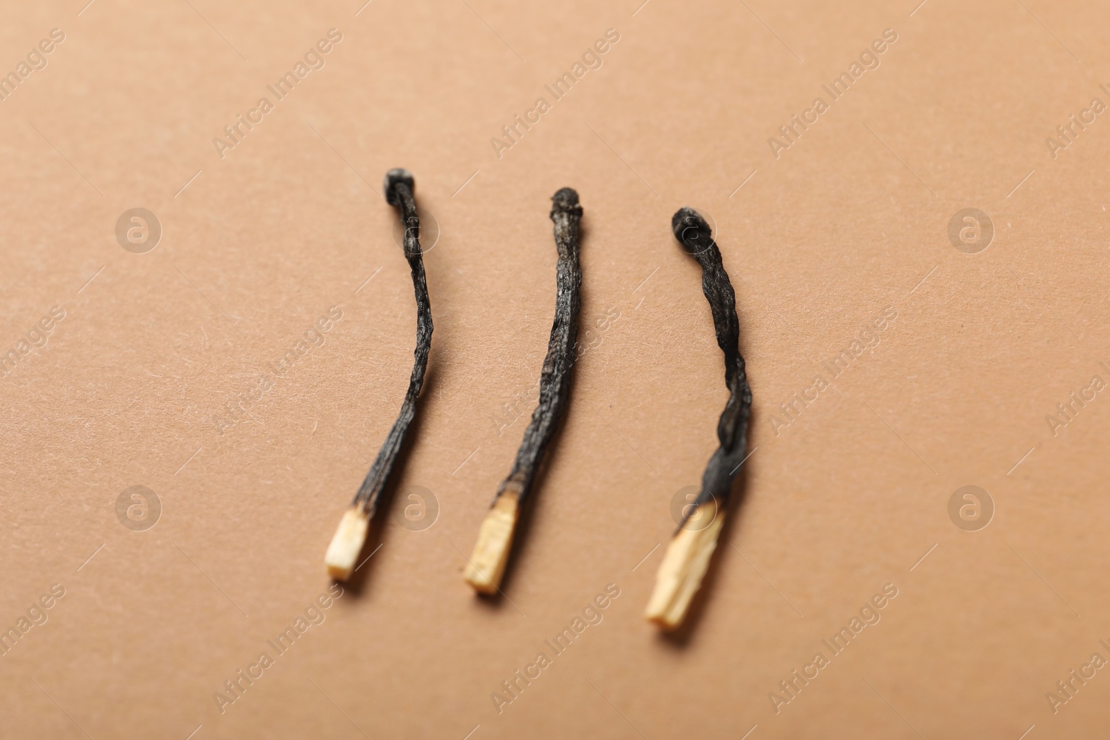 Burnt matches on beige background, closeup view Photo of Burnt matches on beige background, closeup view